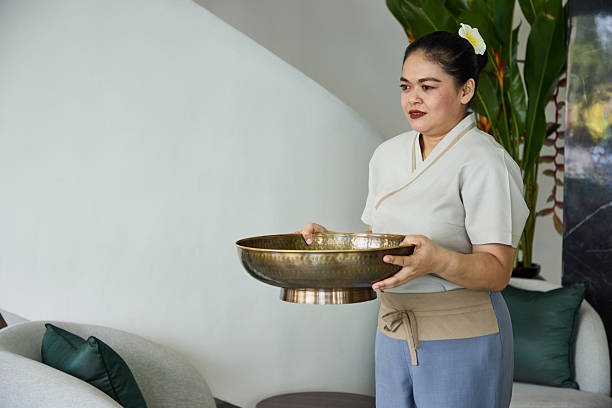 Spa practitioner holding a brass bowl in a serene and peaceful setting, emphasizing relaxation and wellness. Indoor scene with calming decor and a focus on self-care and rejuvenation.