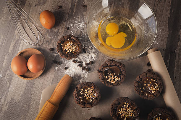 istock Dark brown muffins, eggs, rolling pin, bowl with breaking eggs, whisk, flour and coffee beans on a table, top view. 2213185070
