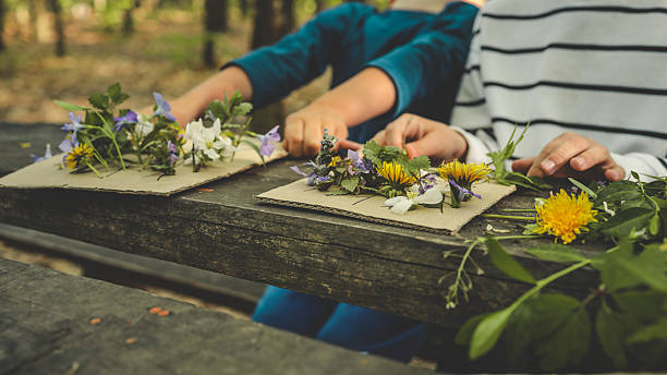 istock Children creating handmade flower crafts using cardboard, drawing vases and attaching real spring blossoms. Creative outdoor activity on a rustic wooden table in the forest 2213188083