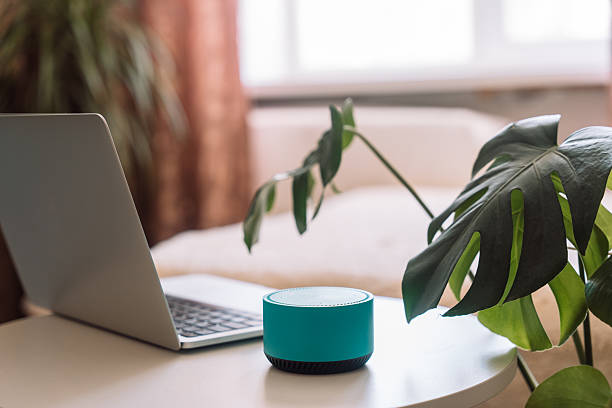 istock Blue wireless smart speaker on white table with laptop in room 2213190266