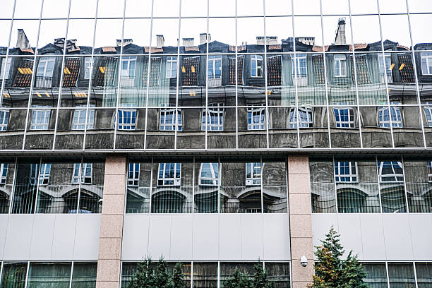 Reflection of a historic building in the glass facade of a modern structure, highlighting the contrast between old and new architecture.