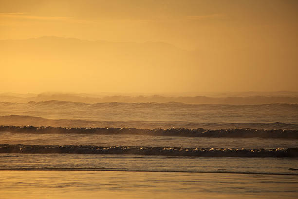 Small waves breaking on water edge, foggy horizon line, sky meeting horizon, Itaguare beach, Bertioga, Brazil