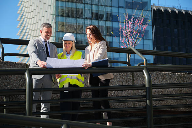 istock Architects and engineers reviewing blueprints outside modern office building 2213205906
