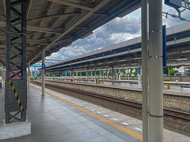 istock A modern train station platform with rows of seating and a shelter overhead, with a cloudy sky above. 2213209274