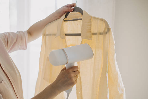 istock Woman Using Steamer to Remove Wrinkles from Shirt 2213209350