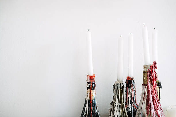 Wine bottles repurposed as candle holders with melted wax dripping down, showcasing a rustic and creative home decor idea. The image emphasizes a vintage and bohemian aesthetic with minimalist design elements.