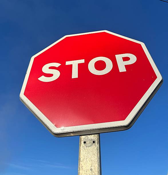 istock Red stop sign standing out against clear blue sky 2213215008