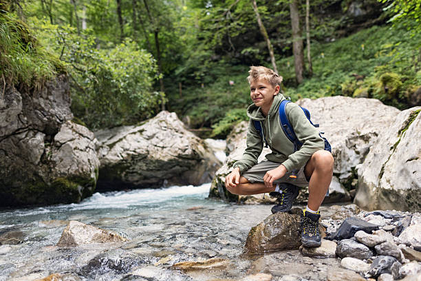 istock Teenage hiker crouching by a forest stream 2213217272