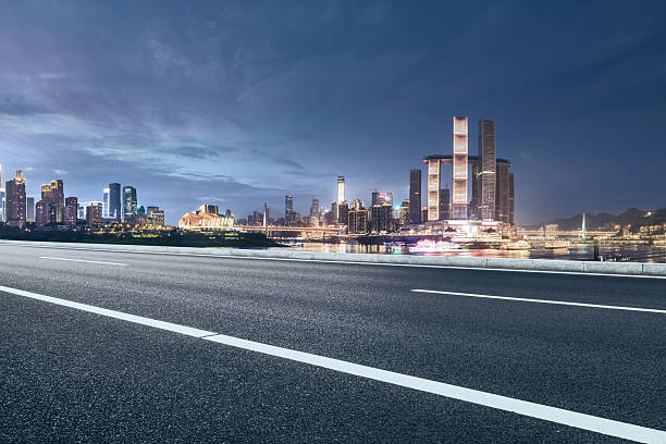 istock Empty asphalt road perspective leads towards illuminated Chongqing city skyline with modern architecture by river at night. 2213217585
