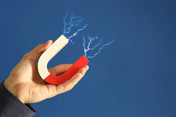 Man holding horseshoe magnet with lightnings on blue background, closeup. Space for text