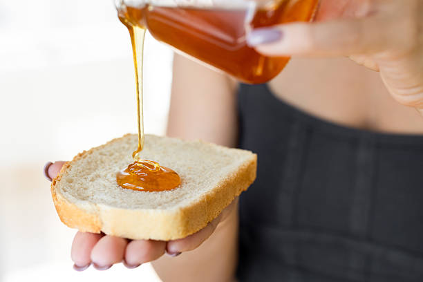 Honey being drizzled onto a thick slice of bread