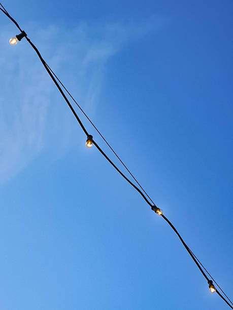 istock A string of decorative glowing light bulbs stretches across a clear blue sky, suggesting themes of celebration, outdoor lighting, or a festive atmosphere 2213223882
