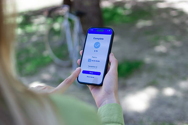 istock Woman completing mobile payment on smartphone in park 2213230730