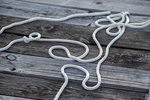 single loose knot of light coloured rope along bottom of frame on rustic wood background with copy space
