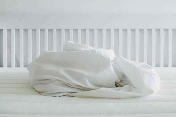 istock Crumpled white bedding on mattress with minimalist white bed frame in soft light 2213233051