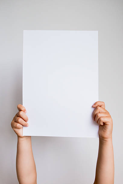 istock Child hands holding blank white paper against wall background 2213233139