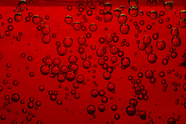 A splash of vivid red liquid caught mid-air, forming an abstract shape with droplets scattering around against a clean white background, frozen in motion with striking detail and texture.