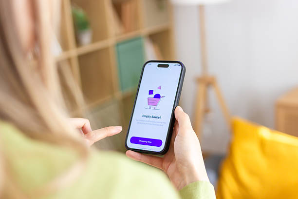 istock Woman using smartphone with empty shopping basket app at home 2213234736