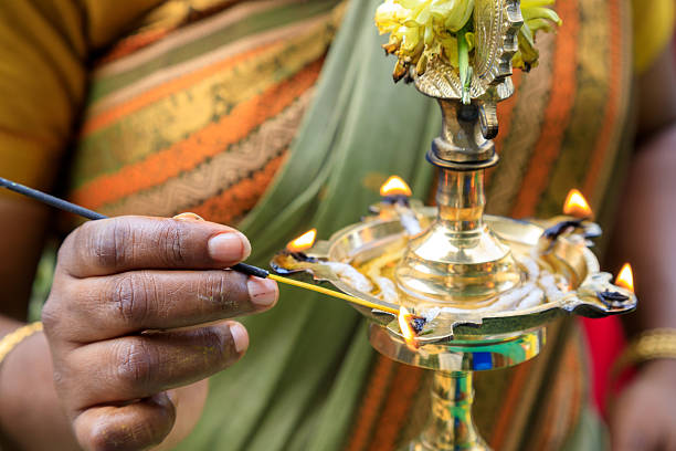 A Tamil devotee lighting a butter lamp in a hindu temple during Thaipusam in Georgetown, Penang, Malaysia.