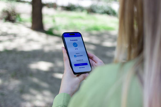 istock Woman completing mobile payment in public park 2213235118