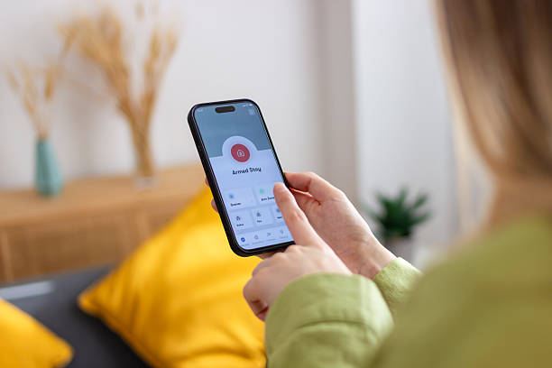 istock Woman using smart home security app on mobile phone at home 2213235253