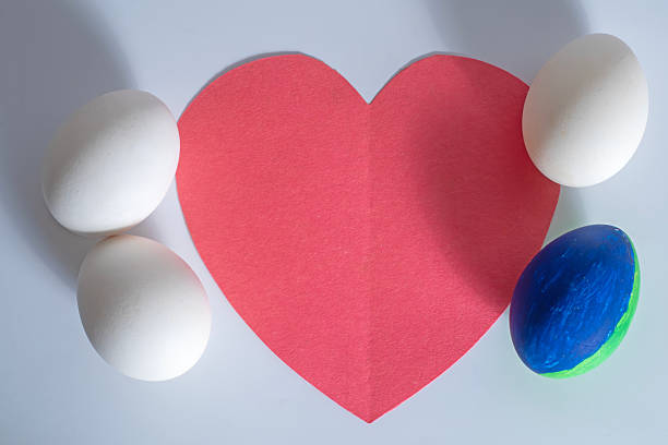 Top view of blue and white eggs placed against a bright red heart-shaped background.