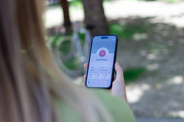 istock Woman using home security app on smartphone outdoors 2213239397