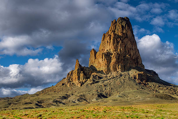 Agathla Peak (7150’), also known as El Capitan, is a prominent geological feature in the American southwest located near Kayenta, Arizona. It is a striking monolithic rock formation that rises abruptly from the surrounding landscape, making it a notable landmark in the region.   Agathla Peak is a volcanic neck, which is the core of an ancient volcano. It formed millions of years ago when molten lava solidified within the vent of a volcano. Over time, erosion exposed the hard volcanic rock, creating the distinctive spire-like formation we see today.  Characterized by its sheer, almost vertical cliffs that rise to a height of about 1,500 feet above the surrounding terrain, the peak's dark, jagged appearance makes it a striking sight against the backdrop of the Arizona desert.  Agathla Peak is in Navajo County just north of Kayenta, Arizona, USA.