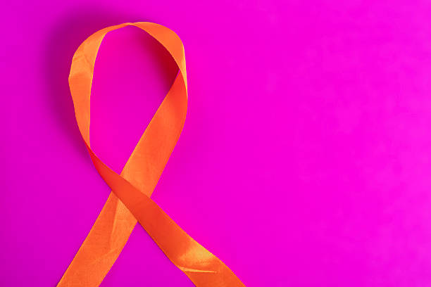 istock Orange awareness ribbon on a vibrant pink background symbolizes support and unity. 2213246679