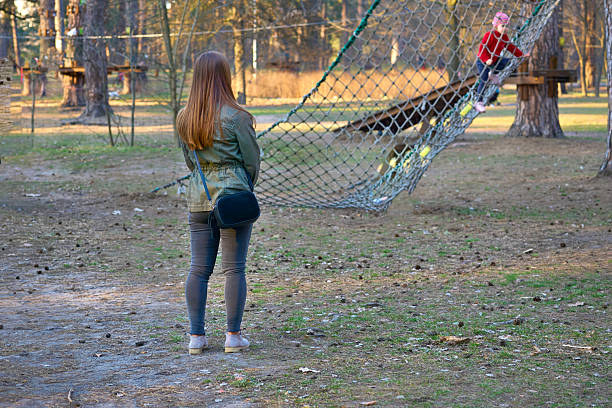 istock Mother in green jacket watching a child playing on the net 2213248056