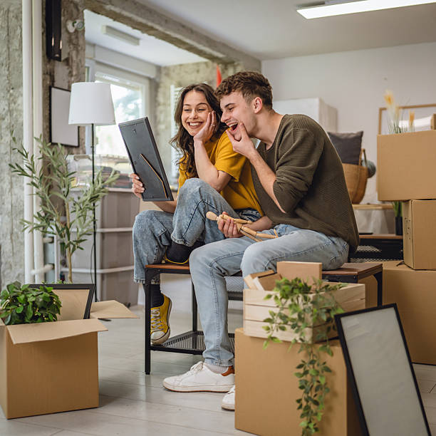 Happy adult couple having fun while unpacking boxes together