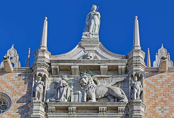 A close-up view of intricately carved architectural column showcasing faces and foliage motifs, located in Venice, Italy.