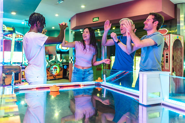 istock Young multiethnic friends celebrating while playing air hockey in an arcade 2213256281
