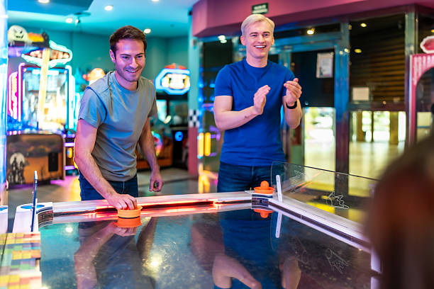 istock Two young men playing air hockey in an amusement arcade 2213256285