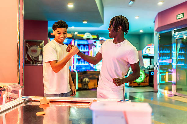 istock Two young men fist bumping while playing air hockey in arcade 2213256331