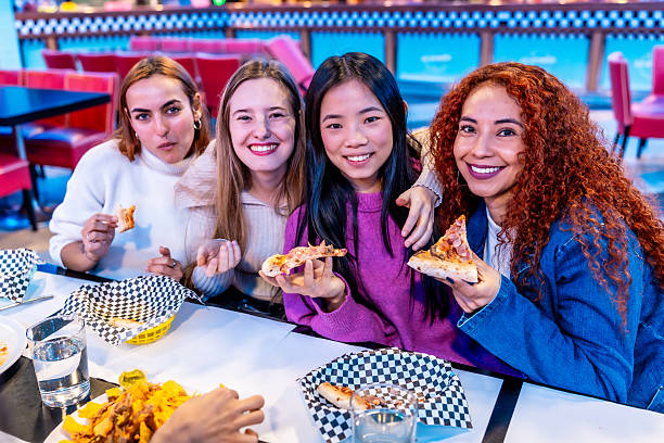 istock Young women eating pizza together in a restaurant 2213256480