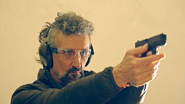 istock Man Firing Handgun. Shooting A Weapon For Defence Training 2213261334