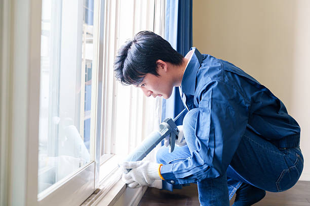 istock Male worker applying caulking material to a window. 2213270073