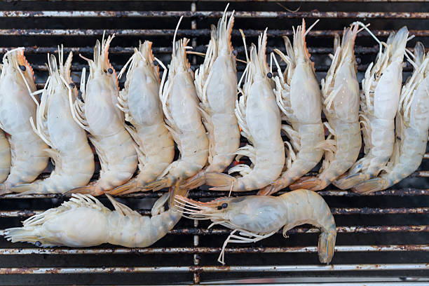 Raw prawns are grilled on the barbecue grill. Top view