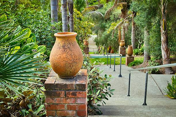Stairway in Bason Botanic Gardens going straight downwards through some gardens. With orange large vases down the stairway.