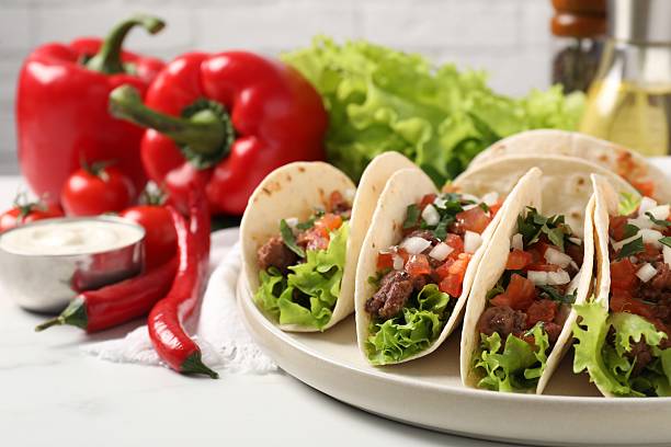 istock Delicious tacos with meat and vegetables on white table, closeup 2213273116