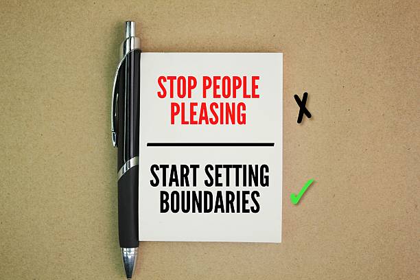 istock pens and books with the words STOP PEOPLE PLEASING - START SETTING BOUNDARIES 2213281616
