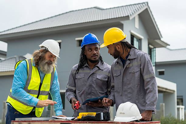 istock Three men in construction gear are standing around a table, looking at blueprints. Scene is serious and focused, as the men are likely discussing plans and strategies for their project 2213287888