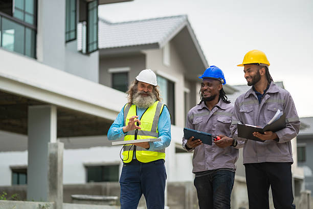istock Three construction workers are walking down a sidewalk, each holding a clipboard. They are wearing safety vests and hard hats, indicating that they are on a job site. Scene is serious and focused 2213287901
