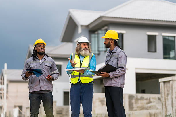 istock Three men in construction gear are standing outside a house, discussing plans. Scene is serious and focused, as the men are likely discussing important details about the construction project 2213287918