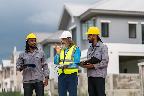 istock Three men in construction gear are standing outside a house, discussing plans. Scene is serious and focused, as the men are likely discussing important details for the construction project 2213287922
