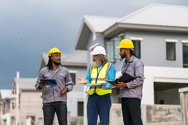istock Three men in construction gear are standing outside a house, discussing plans. Scene is serious and focused, as the men are likely discussing important details for the construction project 2213287923