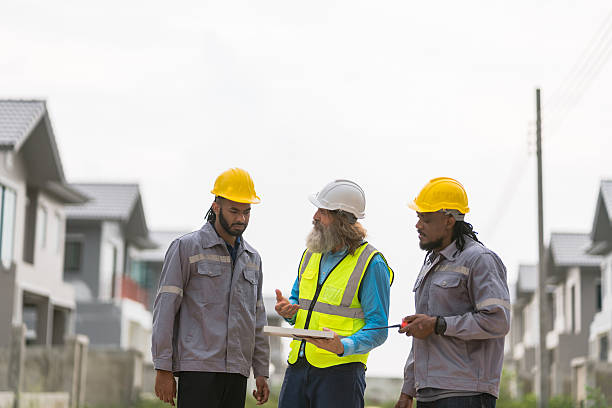 istock Three men in construction gear are standing on a street, discussing plans for a building. Scene is serious and focused, as the men are likely discussing important details for their project 2213287929