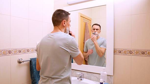 istock Man shaving his mustache with razor in bathroom mirror 2213290039