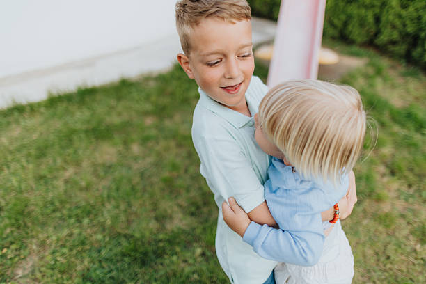 Two beautiful brothers hugging while spending time together in backyard